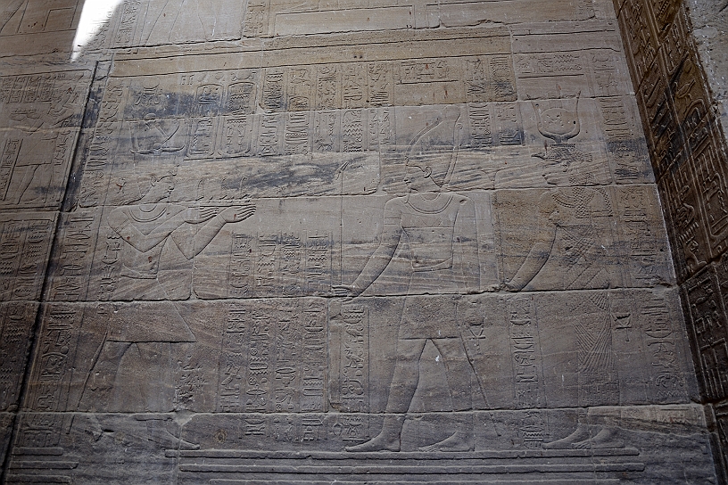 17 MAK_6454.jpg - Sulle pareti vari bassorilievi col Faraone (a sinistra), identificabile dal gonnellino reale, nell'atto di compiere un'offerta. Al centro una figura maschile, probabilmente Horus o Osiride. A destra la dea, Iside riconoscibile dal copricapo.
